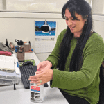 Office worker, customer service manager applies Kemsol Microban hand sanitiser to hands from a 500ml dispenser.